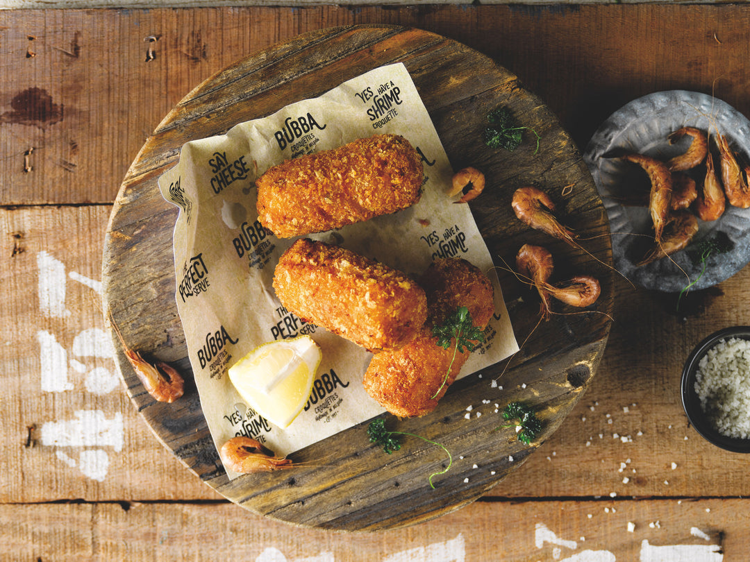 Croquetas de gamba sobre papel Bubba con limón, perejil y gambas grises