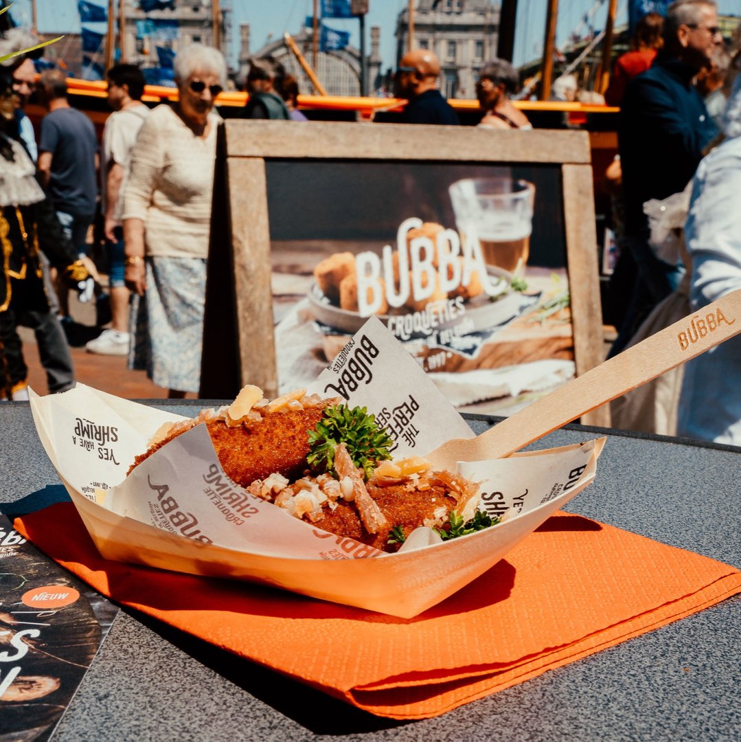 Croquetas Bubba en una barquita de papel en un mercado, con un cartel de Bubba al fondo